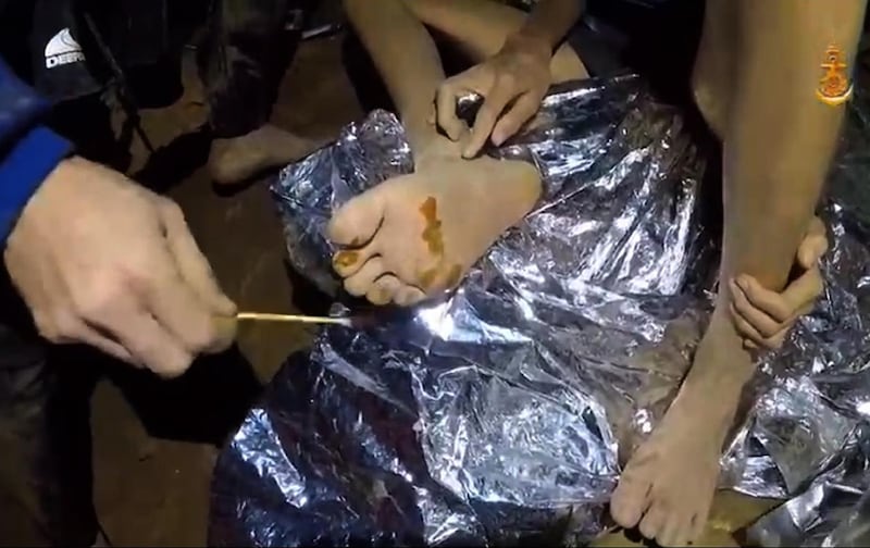 A video grab handout made available by Thai Royal Navy shows a Thai military medic providing first aid to a member of the trapped football team in a section of Tham Luang cave in Khun Nam Nang Non Forest Park. Thai Royal Navy / EPA