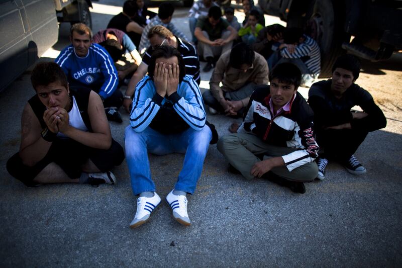 Afghan migrants sit on the ground after being detained by the Greek port police in Lesbos. Uriel Sinai / Getty 