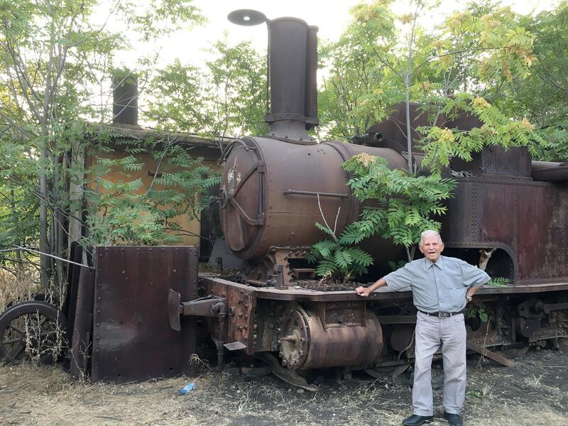 Assad Namroud, 92, is Lebanon's last living train driver. Here he is posing next to a rusting steam train in Riyaq. Photo by Maghie Ghali