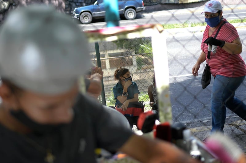 A woman is reflected in a barber shop mirror waiting for her boyfriend who is getting a haircut, near the Miraflores Palace in Caracas, Venezuela. AP Photo