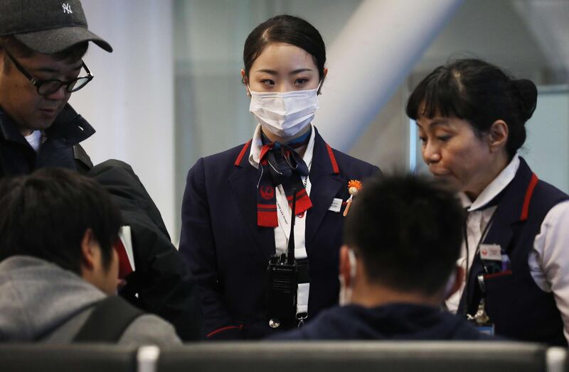 A Japan Airlines worker, centre, wears a face mask while working inside a terminal at Los Angeles International Airport in Los Angeles, California. AFP