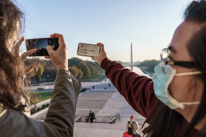 Two friends take pictures as they gather at the Lincoln Memorial at sunrise, the morning after incumbent President Donald Trump was defeated. AP