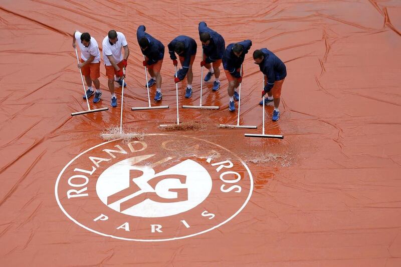 Court workers sweep away rain water at the Suzanne Lenglen court.   REUTERS/Gonzalo Fuentes