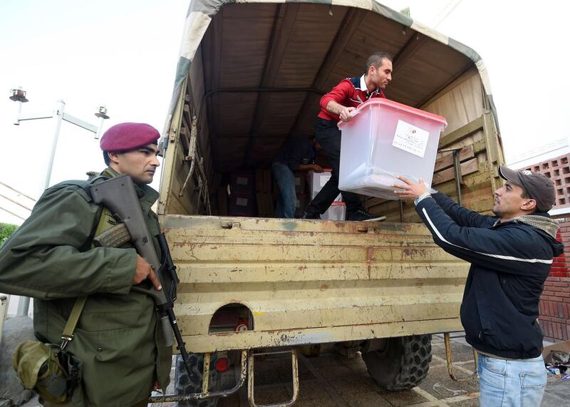 Employees from the Independent High Authority for elections (ISIE) offload ballot boxes from a military vehicle under the surveillance of the Tunisian army, which are to be distributed to polling centres in the governorate of Ben Arous on December 20, 2014. Fethi Belaid/AFP Photo

