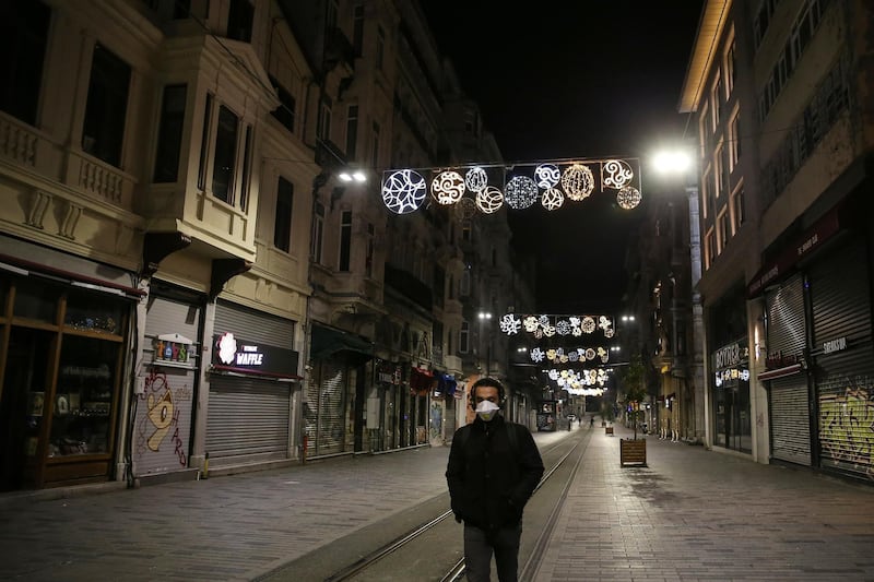 A man wearing a mask to protect against the spread of the coronavirus, walks on the deserted Istiklal Street, the main shopping street in Istanbul. AP Photo