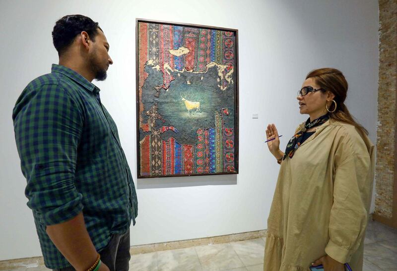 A visitor talks to Libyan artist Elham el-Ferjani in front of one of her works at the Hamim Gallery in the eastern city of Benghazi. The Libyan city is hosting a rare week of culture as the country attempts to turn the page on a decade of violence. AFP