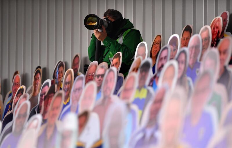 A photographer sits between cardboard cu- out fans during the Sky Bet League One match between AFC Wimbledon and Sunderland at Plough Lane in Wimbledon, England. Getty Images