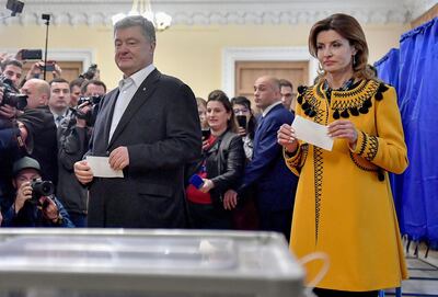 Ukrainian President Petro Poroshenko (L) and his wife Maryna Poroshenko hold their ballot papers to cast into a ballot box at a polling station during the second round of Ukraine's presidential election in Kiev on April 21, 2019.  / AFP / Sergei SUPINSKY
