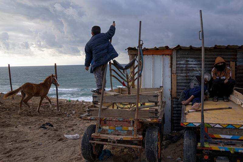 Palestinians outside their home on a rainy day in Dier al-Balah in the Gaza Strip. AP