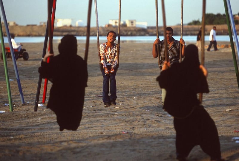 Young men and women on swings on a Jeddah beach in 2002. Alijohani's novel is about difficult relationships in Saudi Arabia. Reza / Getty Images