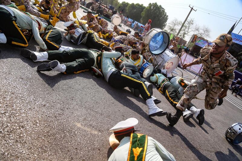 This picture taken on September 22, 2018 in the southwestern Iranian city of Ahvaz shows a soldier running past injured comrades lying on the ground at the scene of an attack on a military parade that was marking the anniversary of the outbreak of its devastating 1980-1988 war with Saddam Hussein's Iraq. Dozens of people were killed with dozens others wounded in an attack in the southwestern Khuzestan province on September 22 targeting on an army parade commemorating the anniversary of the 1980-1988 Iran Iraq war, state media reported. / AFP / ISNA / MORTEZA JABERIAN
