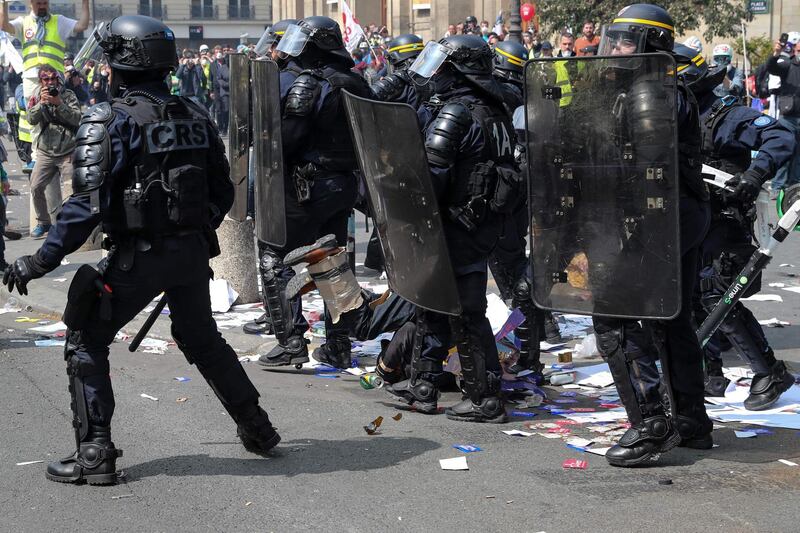 A protester (C) falls on the ground as he is surrounded by riot police officers. AFP