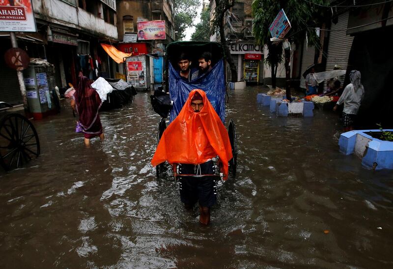A rickshaw puller transports passengers through a water-logged street after heavy rain in Kolkata, India, on June 26, 2018. Rupak De Chowdhuri / Reuters