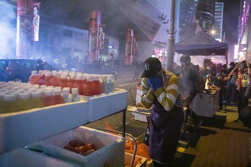 People react after riot police deploy tear gas at a Lunar New Year temporary night market on Portland Street during a protest in the Mong Kok district of Hong Kong, China. Bloomberg