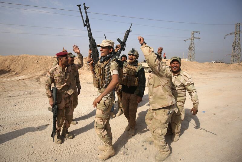 TOPSHOT - Iraqi forces dance on November 4, 2017 near the Syrian border after recapturing the border town of Qaim, west of Anbar, from the Islamic State (IS) group jihadists a day earlier.
Syrian and allied forces converged on holdout Islamic State group fighters in the Syrian border town of Albu Kamal, the jihadists' very last urban bastion following a string of losses. / AFP PHOTO / AHMAD AL-RUBAYE