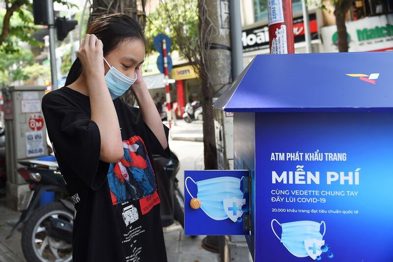 A girl wears a face mask from a 'free mask' dispenser set up along a street, amid concerns over the coronavirus pandemic, in Hanoi.  AFP
