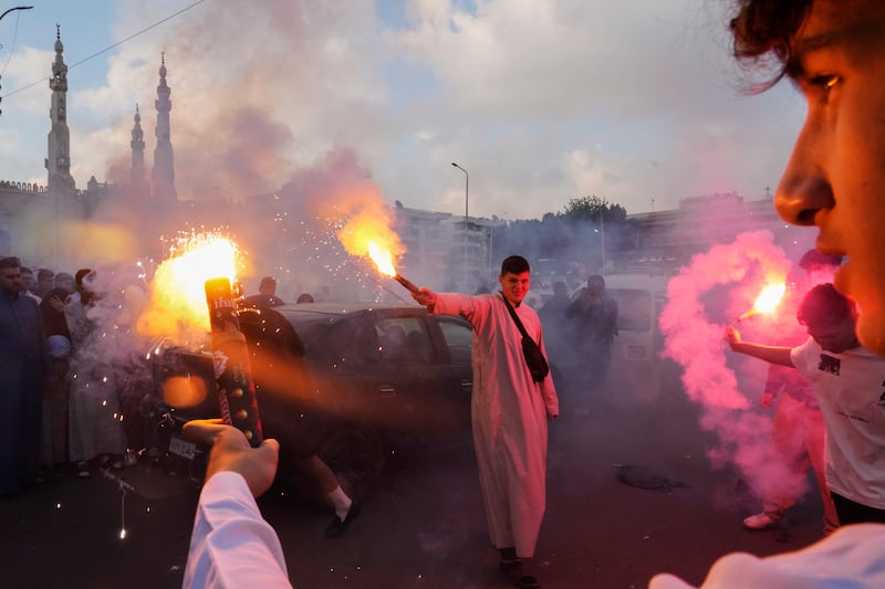 Muslims light flares to celebrate Eid Al Fitr outside Al Seddik mosque in Cairo, Egypt. AP