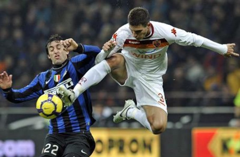 Roma's Marco Andreolli, goes airborne to take the ball away from Inter's Diego Milito on Sunday.