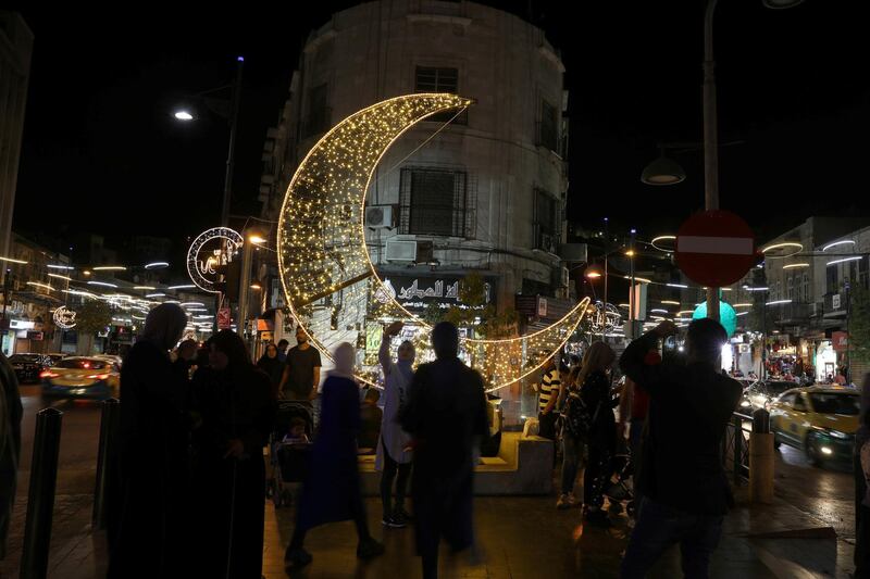 People take pictures of an illuminated crescent, a decoration made for the holy fasting month of Ramadan in Amman, Jordan. REUTERS