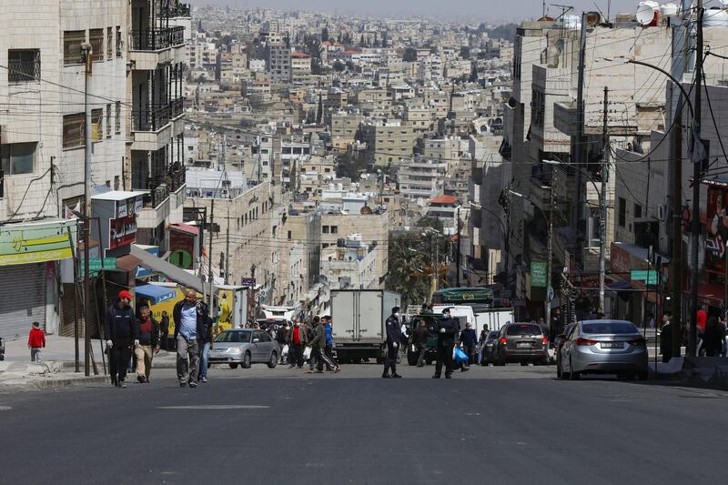 Jordanian police officers are seen at a checkpoint as people walk in the street after Jordan announced it would allow people to go on foot to buy groceries in neighborhood shops, amid concerns over the spread of coronavirus disease (COVID-19), in Amman, Jordan March 25, 2020. REUTERS/Muhammad Hamed