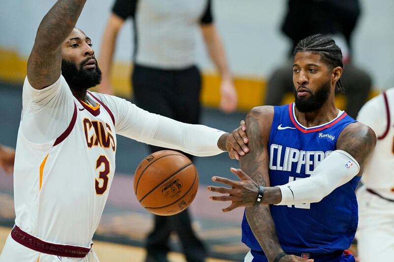 Los Angeles Clippers' Paul George, right, passes against Cleveland Cavaliers' Andre Drummond in the second half of an NBA basketball game, Wednesday, Feb. 3, 2021, in Cleveland. The Clippers won 121-99. (AP Photo/Tony Dejak)