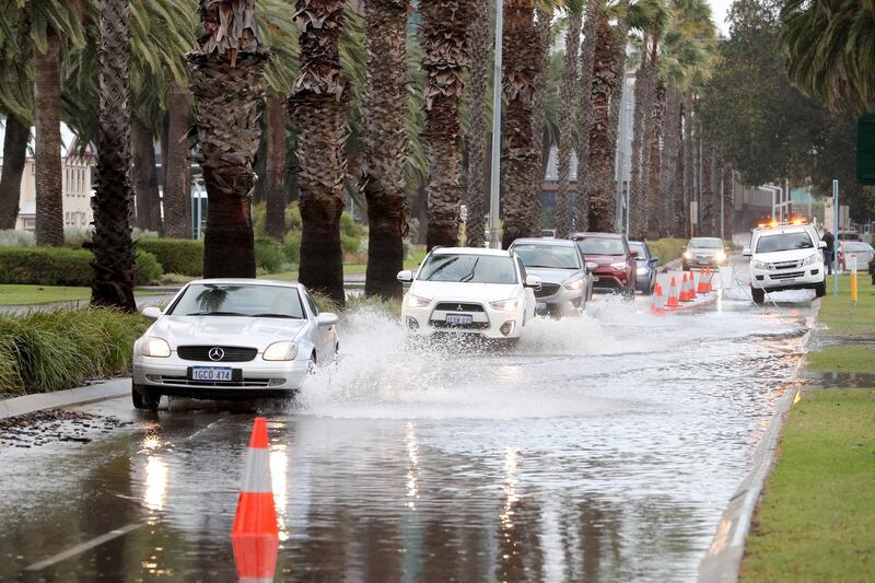 Vehicles navigate floodwater on Riverside Drive near the Swan River, which is partially closed due to storm flooding, in Perth, Western Australia.  EPA