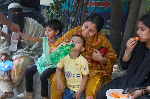 Children drink from water bottles in a heatwave in Dhaka. EPA