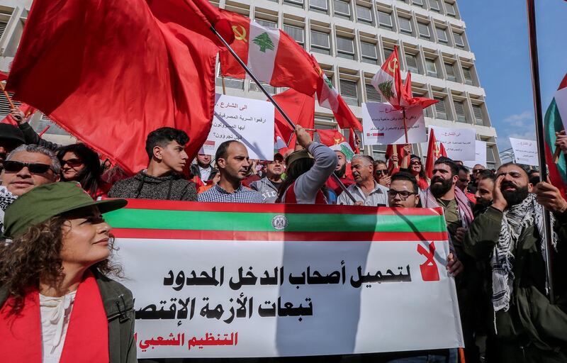 epa07235430 Supporters of the Lebanese communist party hold a placard reading in Arabic 'No for loading low-income citizens the consequences of the economic crisis' during their protest in Beirut, Lebanon, 16 December 2018. Hundreds of protesters from the National Union of Trade Unions and Users in Lebanon, led by the Lebanese Communist Party and the Lebanese Democratic Youth Union, protested in front of the headquarters of the Banque du Liban and marched towards down town Beirut, rejecting unfair taxes on gasoline and value added (TVA) and all indirect taxes, calling on the government to protect citizens right to work and right to have access to medical care.  EPA/NABIL MOUNZER
