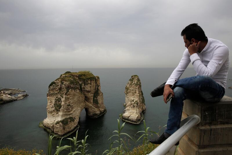 A man looks towards the Mediterranean Sea and the landmark Rock of Raouché, also know as Pigeons' Rock, which is a popular destination for Lebanese and visitors, in Beirut, Lebanon. AP Photo