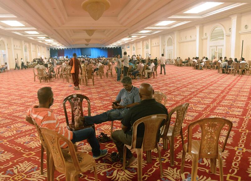Supporters of ousted Sri Lanka's Prime Minister Ranil Wickremesinghe sit inside a large room at the Prime Minister's official residence in Colombo.   AFP