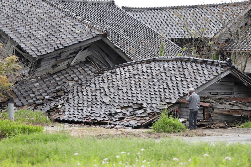 A man examines the ruins of house that collapsed after a 6.5 magnitude earthquake hit the city of Suzu, Ishikawa prefecture, in Japan on Friday, killing one person. AFP