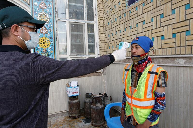 A member of the medical team checks the temperature of a municipality worker, amid the coronavirus disease (COVID-19) outbreak, in the holy city of Najaf, Iraq February 15, 2021. REUTERS/Alaa al-Marjani