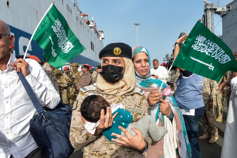 A baby is cradled by a Saudi Navy servicewoman as evacuees arrive at King Faisal Navy Base in Jeddah. AFP