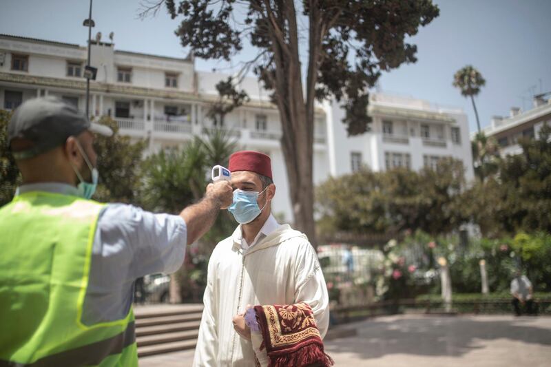 A worker checks the temperature of people who are going to pray at a mosque in Rabat, Morocco. With the exception of Friday prayer, mosques reopened for the first time since their closure in March following the coronavirus outbreak. AP Photo