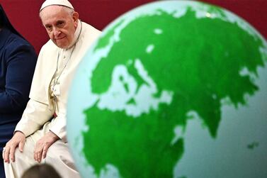 Pope Francis looks at a globe of the Earth during an audience for children and families of the Santa Marta dispensary. AFP