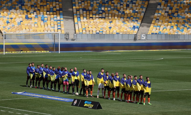 Players draped in Ukrainian flags line up before the Ukrainian Premier League match between Shakhtar Donetsk and Metalist 1925 at Kyiv’s Olympic Stadium on Tuesday, August 23, 2022. Reuters