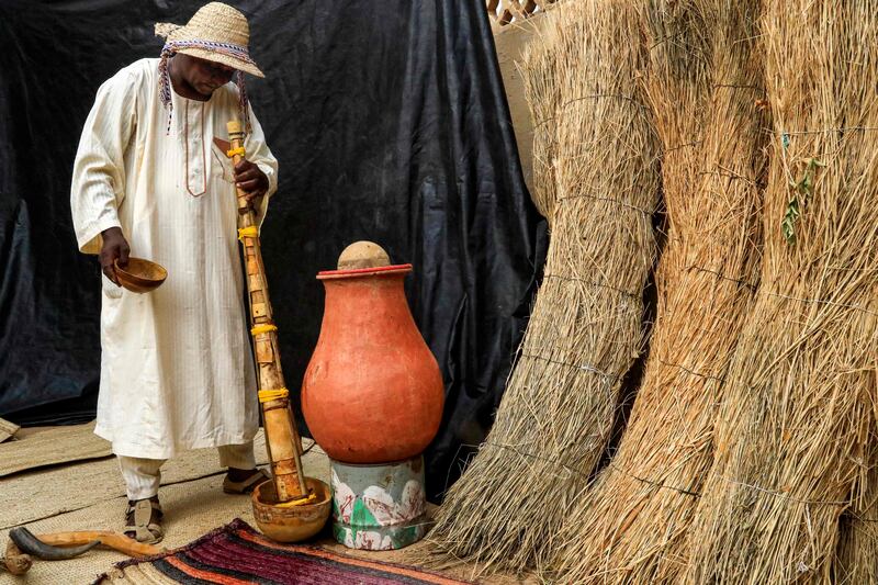 Ali Mustafa pours water down the pipe of the traditional wazza instrument to wet and soften it before playing.