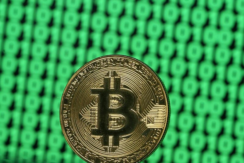 FILE PHOTO: A token of the virtual currency Bitcoin is seen placed on a monitor that displays binary digits in this illustration picture, December 8, 2017.  REUTERS/Dado Ruvic/Illustration/File Photo