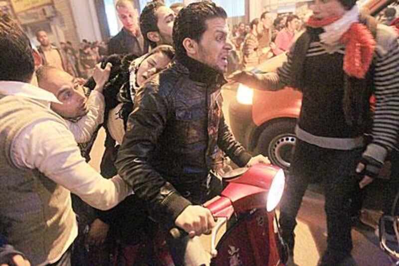 A female protester is evacuated by motorcycle as police use tear gas on protesters in Cairo after 74 football fans were killed in riots in Port Said on Wednesday night.