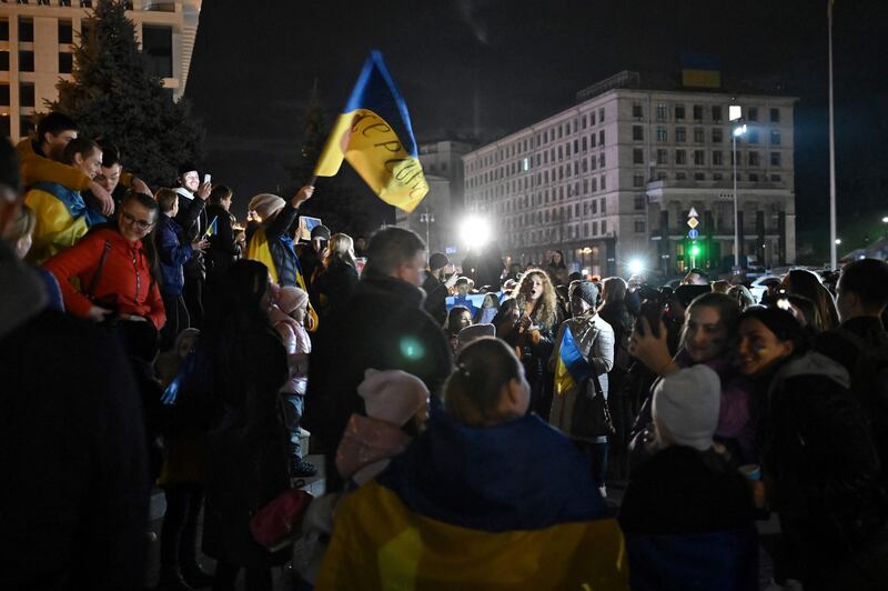 People hold a Ukranian flag as they gather in Maidan square to celebrate the liberation of Kherson, in Kyiv.  AFP