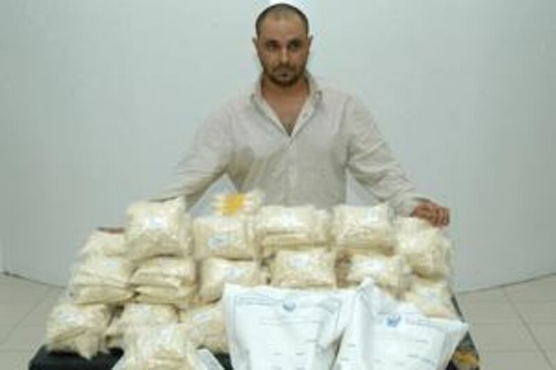 The suspect stands behind the seized half a million Captagon pills.
