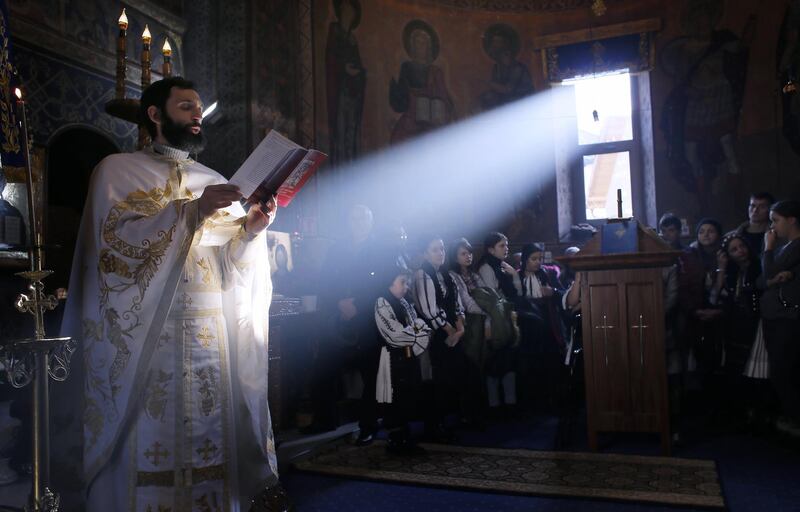 A Romanian Orthodox priest (L) sings to faithful during the Christmas Day mass held at the Orthodox church of Malaia village, Romania.  EPA/ROBERT GHEMENT