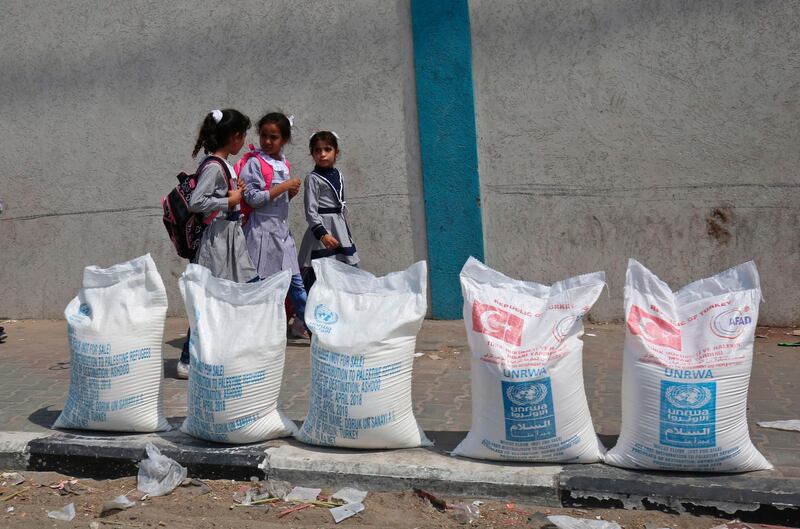 Palestinian school girls walk past sacks of flour outside a United Nations' compound at the Rafah refugee camp in the southern Gaza Strip on September 1, 2018. - The United States announced it was halting funding for the United Nations' agency for Palestinian refugees after declaring the organisation was "irredeemably flawed. Washington has long been the UN Relief and Works Agency's (UNRWA) largest donor but is "no longer willing to shoulder the very disproportionate share of the burden," State Department spokeswoman Heather Nauert said in a statement. (Photo by SAID KHATIB / AFP)