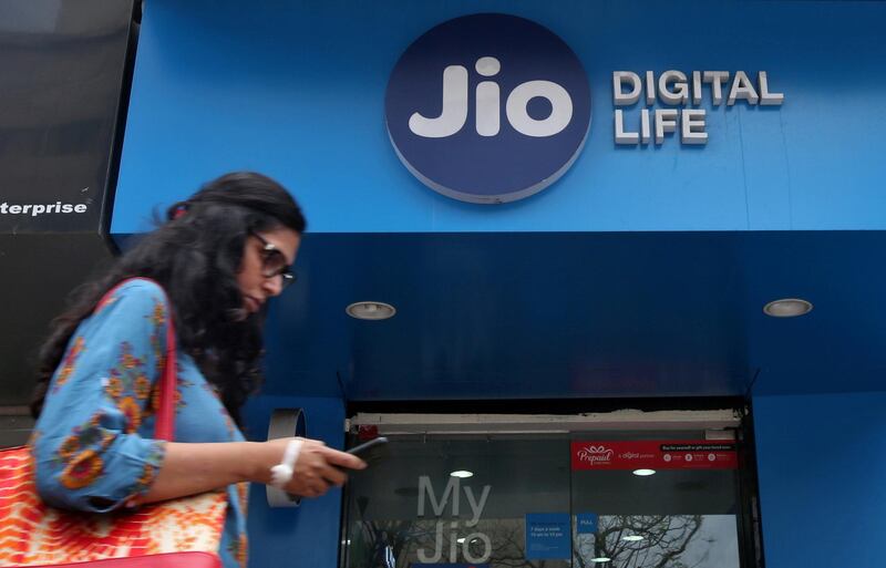 FILE PHOTO: A woman checks her mobile phone as she walks past a mobile store of Reliance Industries' Jio telecoms unit, in Mumbai, India, July 11, 2017. REUTERS/Shailesh Andrade/File Photo