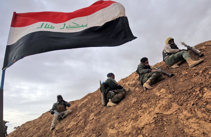 Fighters from the Shiite Hashed Al Shaabi paramilitary unit sit under an Iraqi flag as they get ready to advance towards the village of Shwah, south of the city of Tal Afar on the western outskirts of Mosul. Ahmad Al Rubaye / AFP Photo