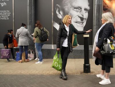WINDSOR, UNITED KINGDOM - APRIL 16: Shoppers chat next to a photograph commemorating Prince Philip, Duke of Edinburgh, on the window of Marks & Spencer in Windsor High Street on April 16, 2021 in Windsor, United Kingdom. The Queen announced the death of her beloved husband, His Royal Highness Prince Philip, Duke of Edinburgh. HRH passed away peacefully on April 9th at Windsor Castle. (Photo by Christopher Furlong/Getty Images)