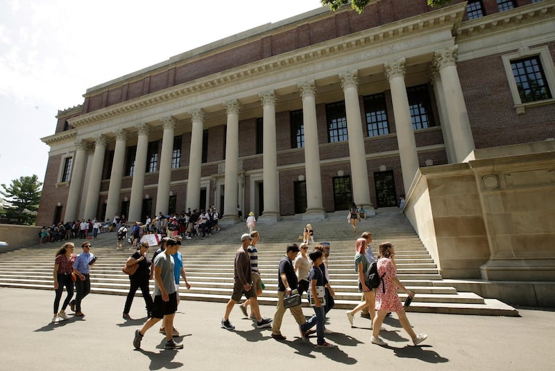 FILE - In this July 16, 2019, file photo people walk past an entrance to Widener Library, behind, on the campus of Harvard University, in Cambridge, Mass. Even with a fresh victory on behalf of international students, U.S. universities fear they��������re losing a broader fight over the nation��������s reputation as a place that embraces and fosters the world��������s best scholars. (AP Photo/Steven Senne, File)