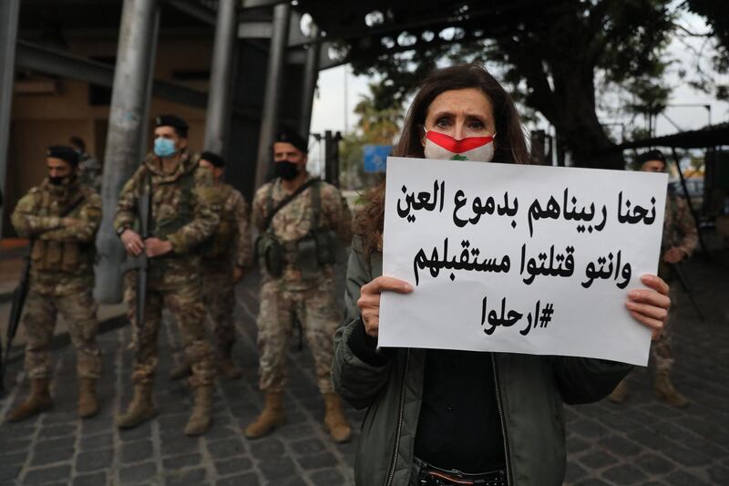 A Lebanese woman holds a placard in front of soldiers during a protest against the country's political paralysis and deep economic crisis in Beirut on the occasion of Mother's Day. AFP