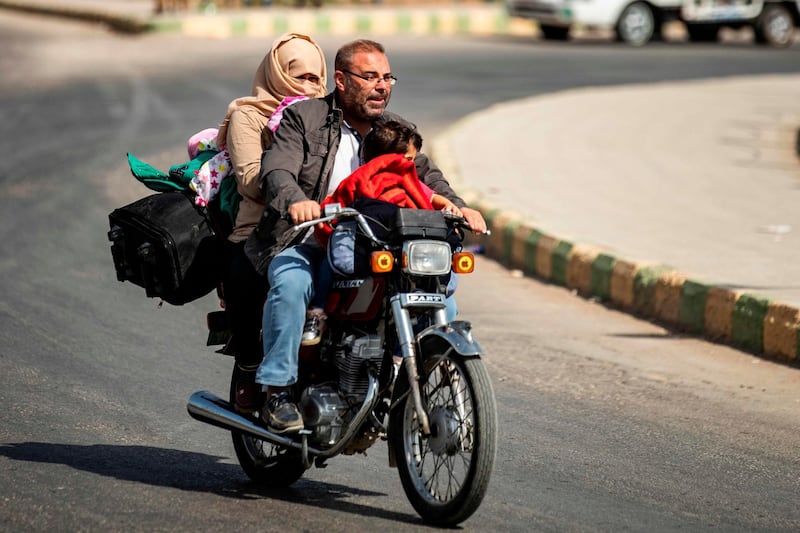 Displaced Syrians ride a motorcycle Arab and Kurdish civilians flee amid Turkey's military assault on Kurdish-controlled areas in northeastern Syria in the Syrian border town of Tal Abyad. AFP