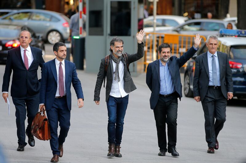 Jordi Cuixart, president of the Catalan Omnium Cultural organization, center, and Jordi Sanchez, president of the Catalan National Assembly, fourth from left wave to supporters on arrival at the national court in Madrid, Spain, in Madrid, Spain, Monday, Oct. 16, 2017. Two senior Catalan regional police force officers and the leaders of two pro-independence associations are in court again, facing possible sedition charges related to the staging of the region's banned Oct. 1 secession referendum. The sedition case is investigating the roles of the four in Sept. 20-21 demonstrations in Barcelona as Spanish police arrested several Catalan officials and raided offices in a crackdown on referendum preparations. (AP Photo/Paul White)